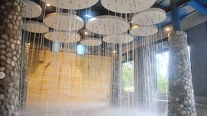 Un élément décoratif aquatique composé de plusieurs plateformes circulaires et d’un mur en pierre.