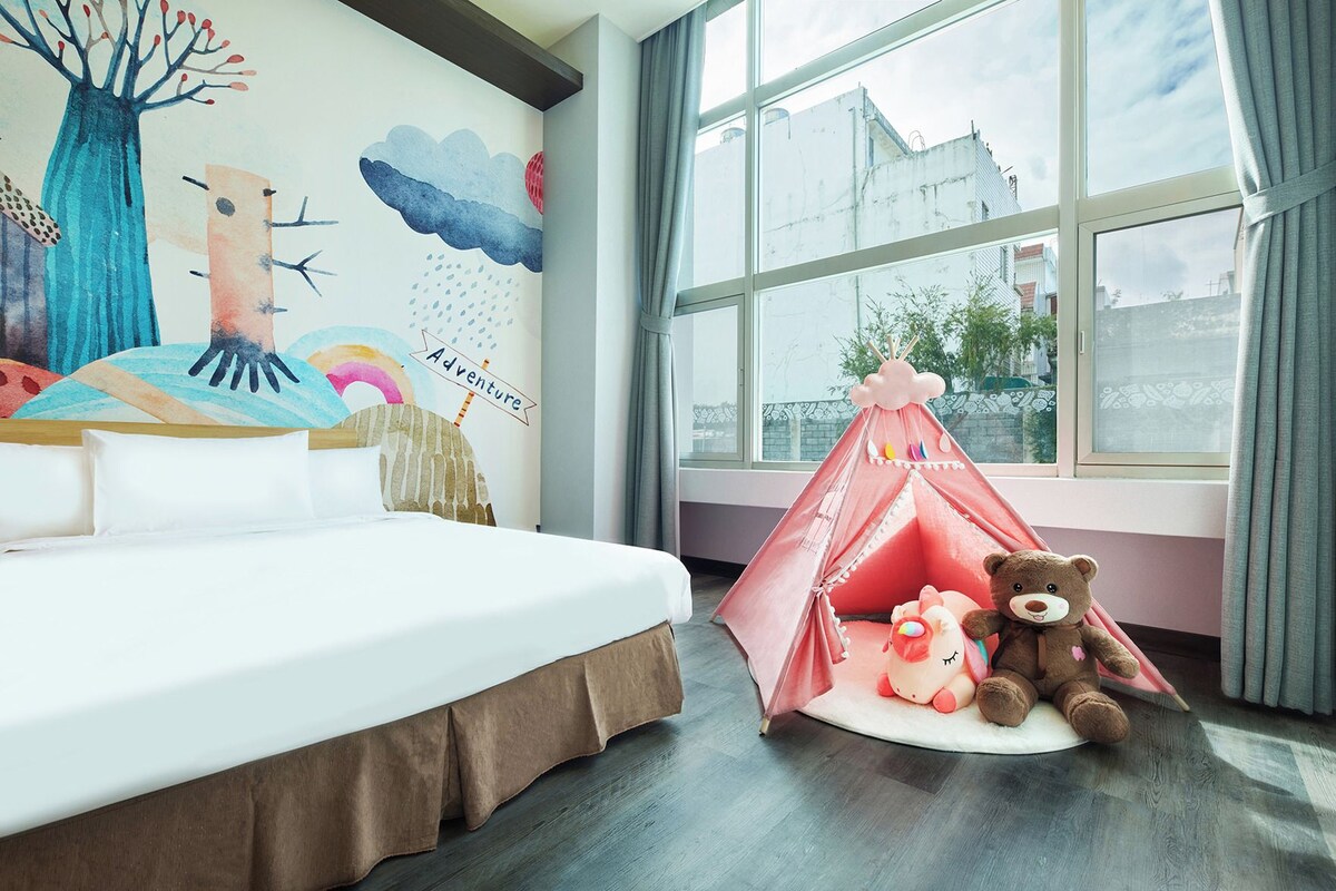 Un dormitorio con cama, un mural en la pared, una ventana y una tienda de campaña con peluches.