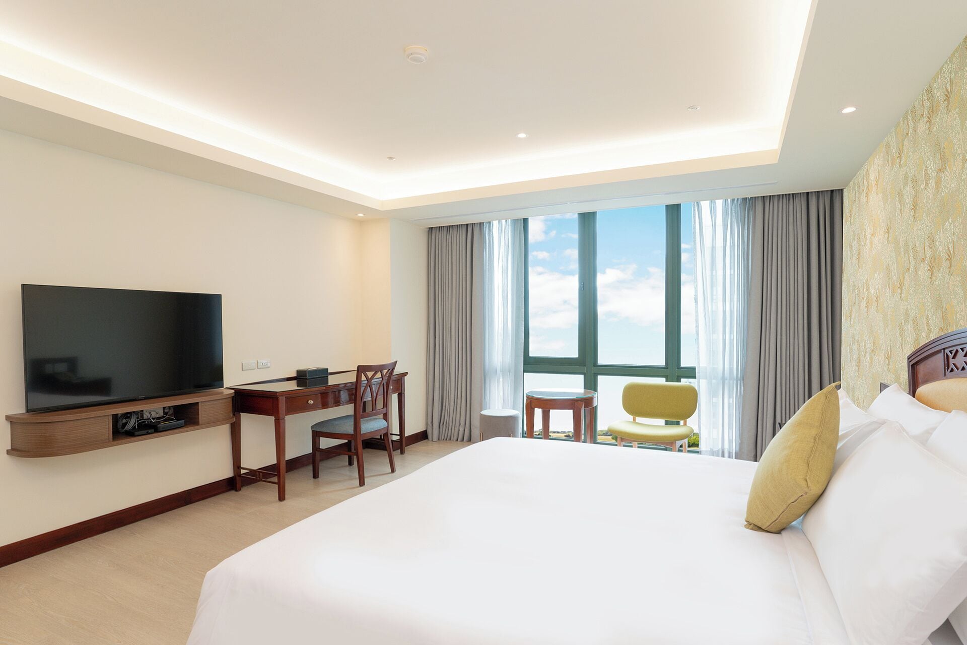 A hotel room with a bed, a TV, a desk, and a chair.