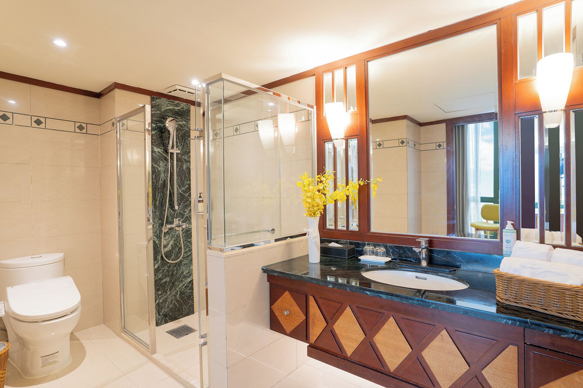 A modern bathroom with a glass-enclosed shower, a white toilet, a marble countertop, and a large mirror.