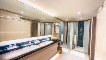 A modern bathroom with a large mirror, two sinks, a shower, and a vanity area.