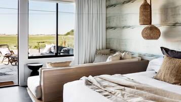 A bedroom with a large window, a bed, a sofa, and a hanging light fixture.