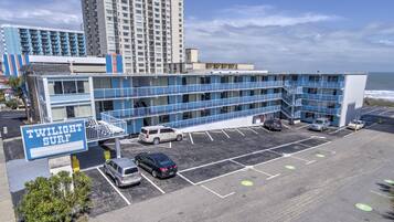 A multi-story motel with a sign reading "Twilight Surf" and a parking lot with several cars.