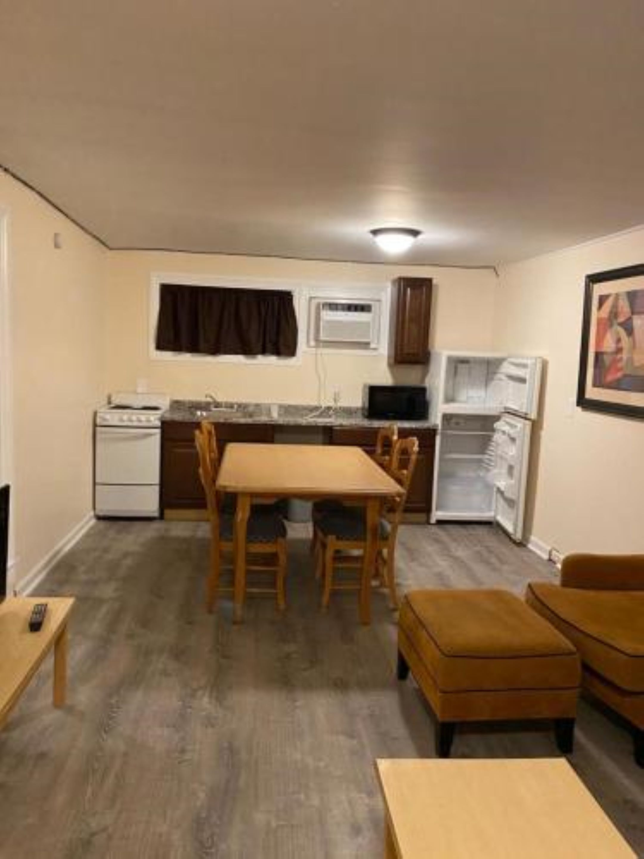 A compact kitchen with a dining area, a refrigerator, a microwave, and a small oven.