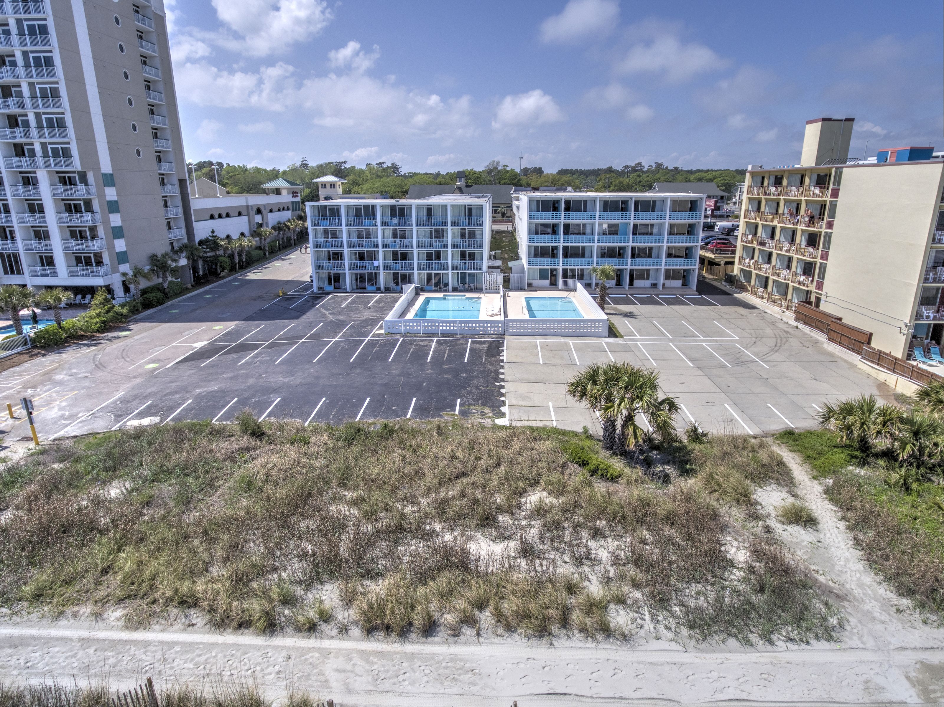 A hotel with multiple floors, a swimming pool, and a parking lot.