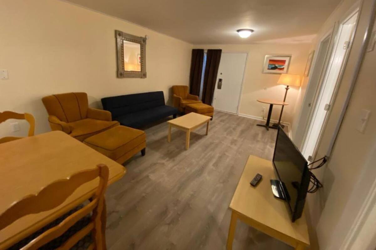 Un salon avec un canapé, des fauteuils, une table basse, un téléviseur et une lampe.