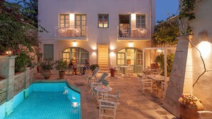 Ein zweistöckiges Gebäude mit Pool, Sitzgelegenheiten im Freien und einem Balkon.