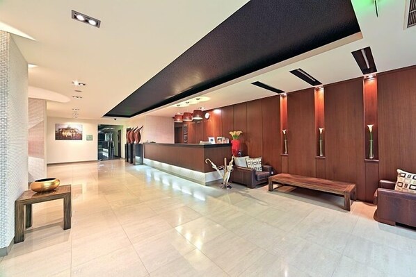 A modern lobby with a reception desk, seating area, and a decorative vase.