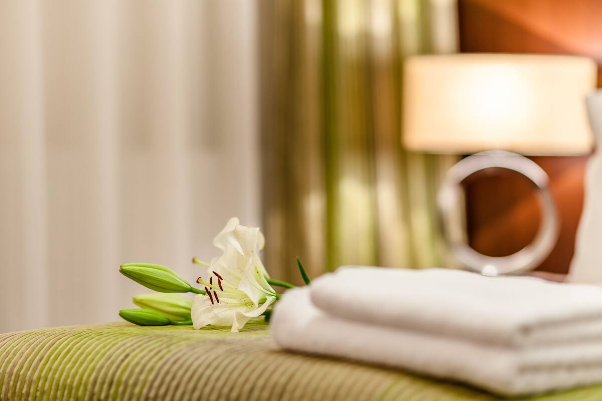 A neatly arranged bathroom with a towel, a flower, and a lamp.