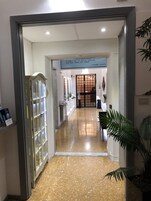 Een gang met een gepolijste vloer, een glazen vitrine en een deur naar een andere kamer.