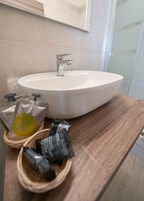 Een badkamer met een wit wastafelmeubel, een spiegel erboven en een houten aanrechtblad.