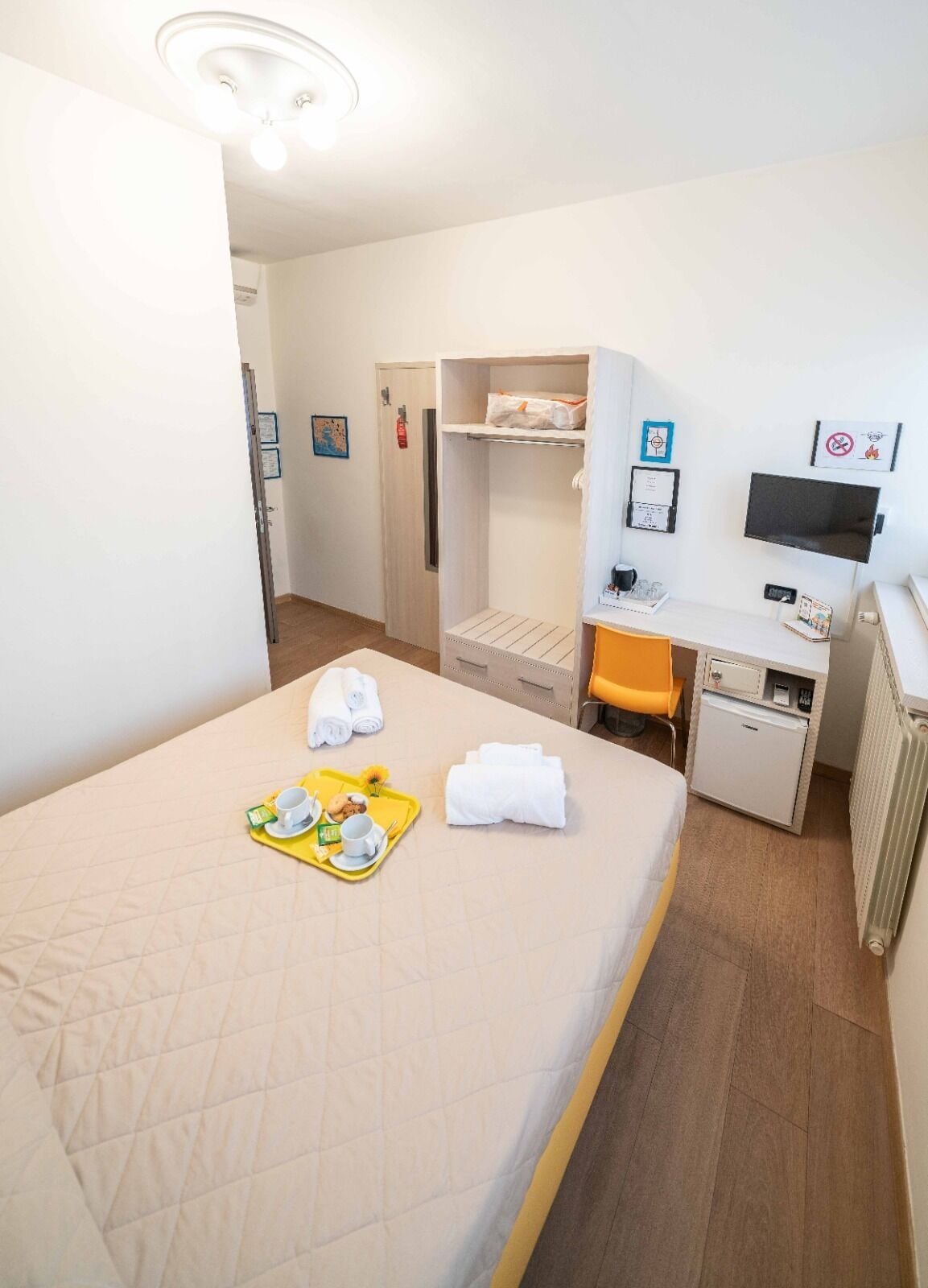 Habitación de hotel con cama, escritorio, un refrigerador pequeño y zona de ducha.
