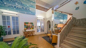 A spacious lobby with a wooden staircase, a reception desk, and a large mural on the ceiling. - Hotel Cairoli (Genoa)