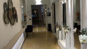 A hotel corridor with a sign reading "HOTEL CAIROLI," a polished floor, and wall-mounted decorations. - Hotel Cairoli (Genoa)