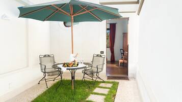 A patio with a table and chairs, an umbrella, and a small garden area.