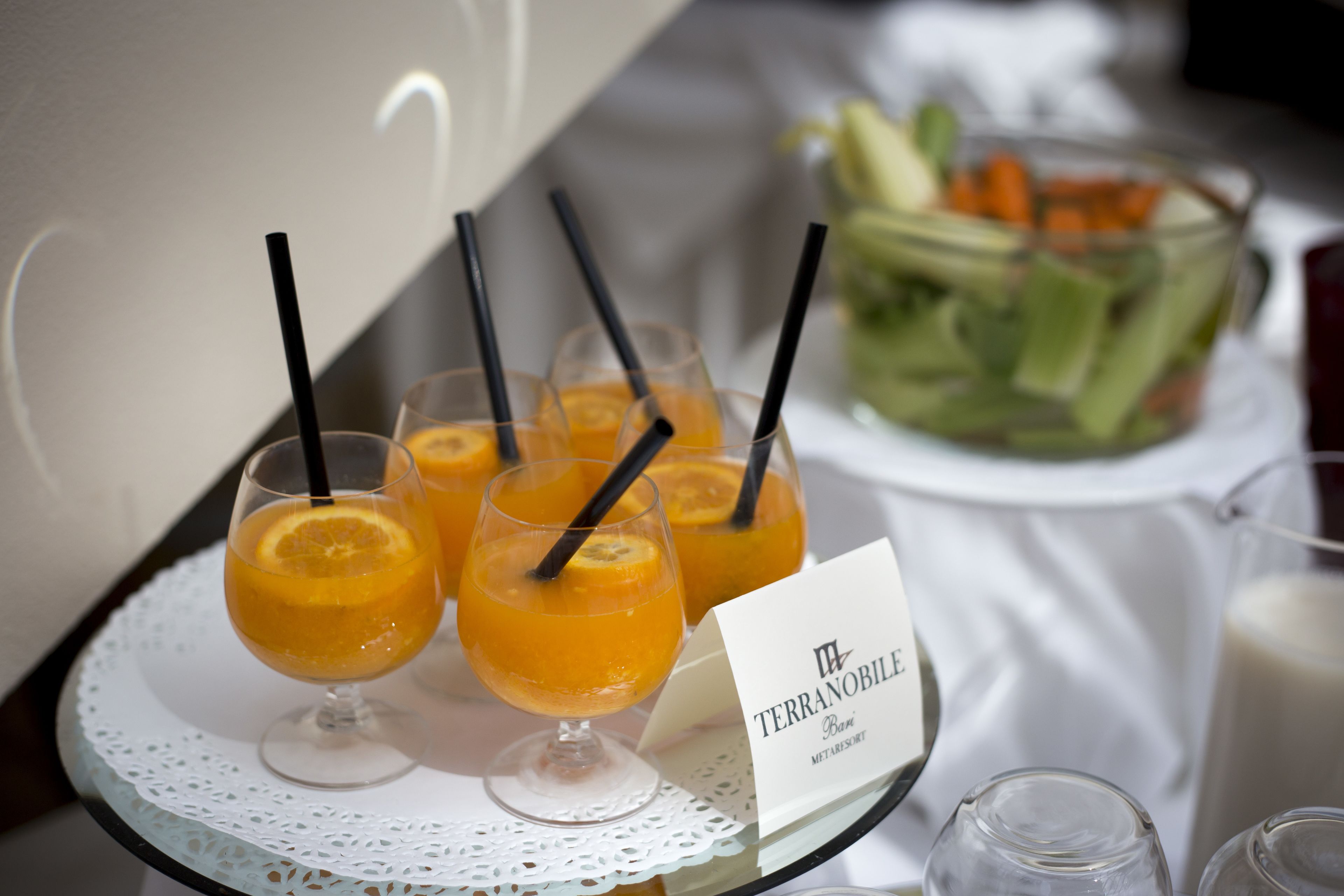 A tray with three glasses of orange juice, a bowl of salad, and a milk pitcher.