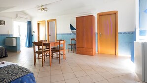 A room with a dining table, chairs, a wardrobe, and a ceiling fan. - Hotel Immagine (San Giovanni Rotondo)
