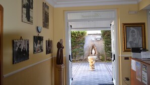 A hallway with a statue, framed pictures, and a sign reading "Benedictine." - Hotel Immagine (San Giovanni Rotondo)