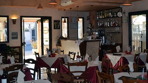 A restaurant with multiple tables and chairs, a bar area, and a view of the street outside. - Hotel Immagine (San Giovanni Rotondo)