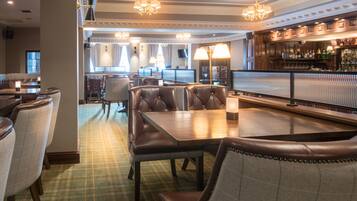 A restaurant with leather seating, a bar area, and a television screen.