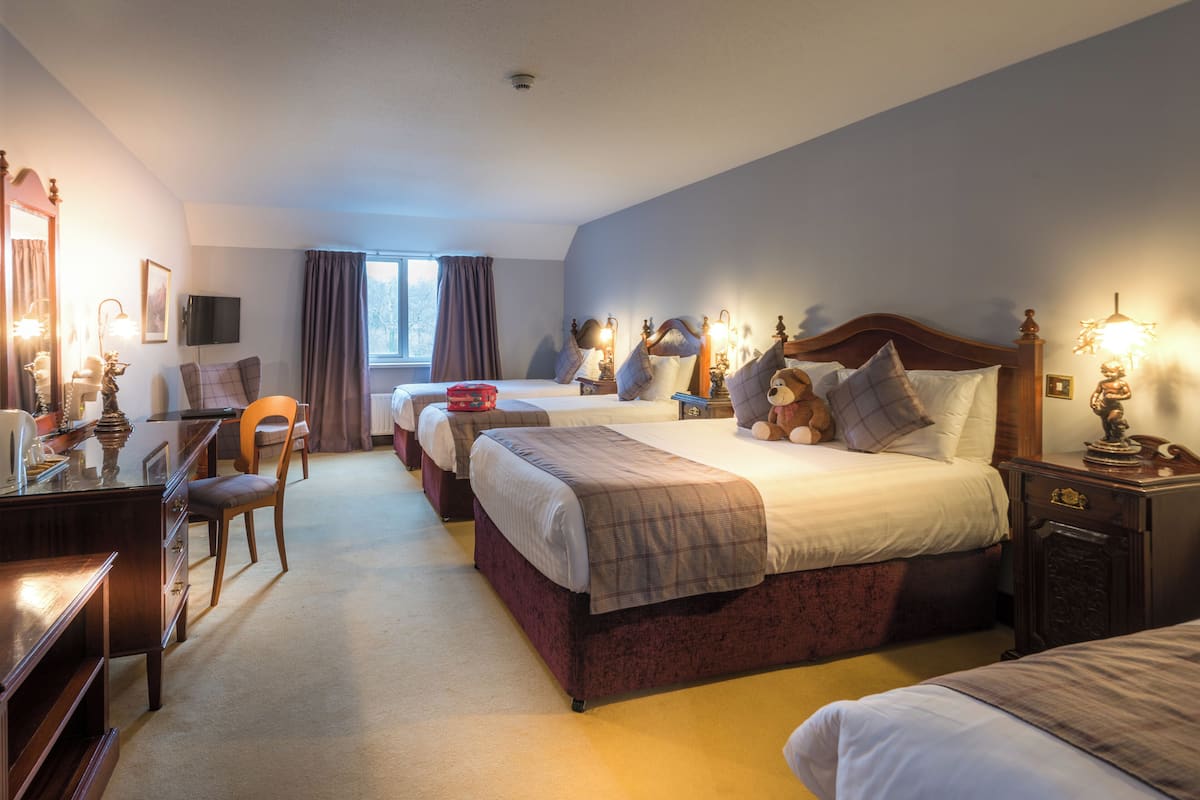 Une chambre d’hôtel avec deux lits, un bureau, une chaise et un téléviseur.