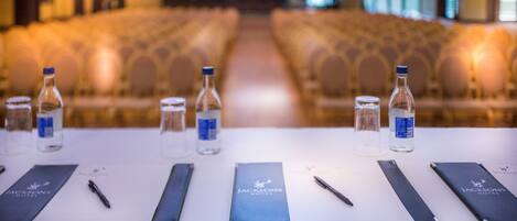 A conference room with rows of chairs, water bottles, notepads, and pens on a table.