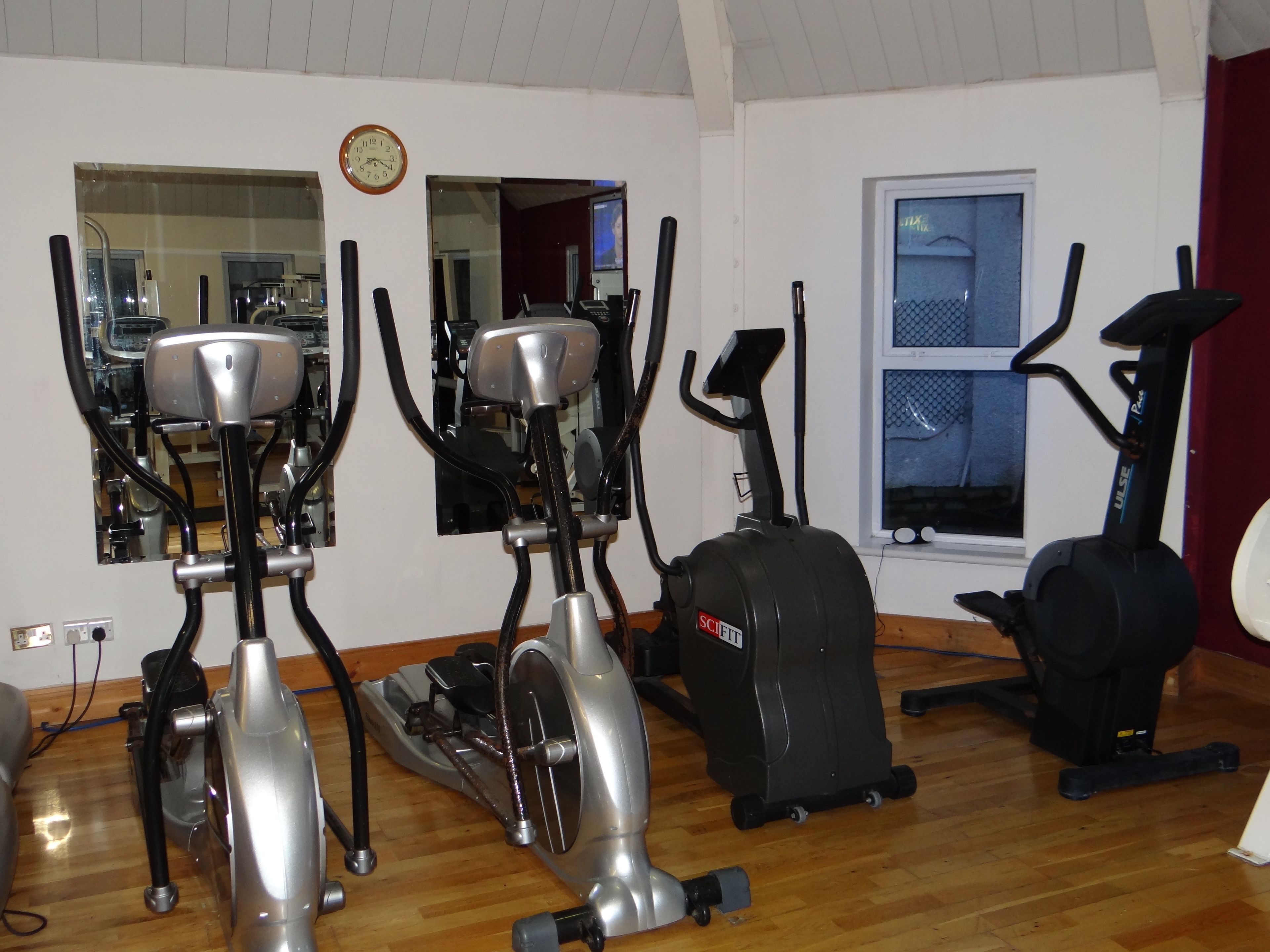 A home gym with various exercise equipment including stationary bikes, an elliptical trainer, and a treadmill.