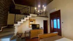 A bedroom with a bed, a dresser, a television, and a staircase leading to an upper level. - Estrella de Belem (San Pedro Cholula)