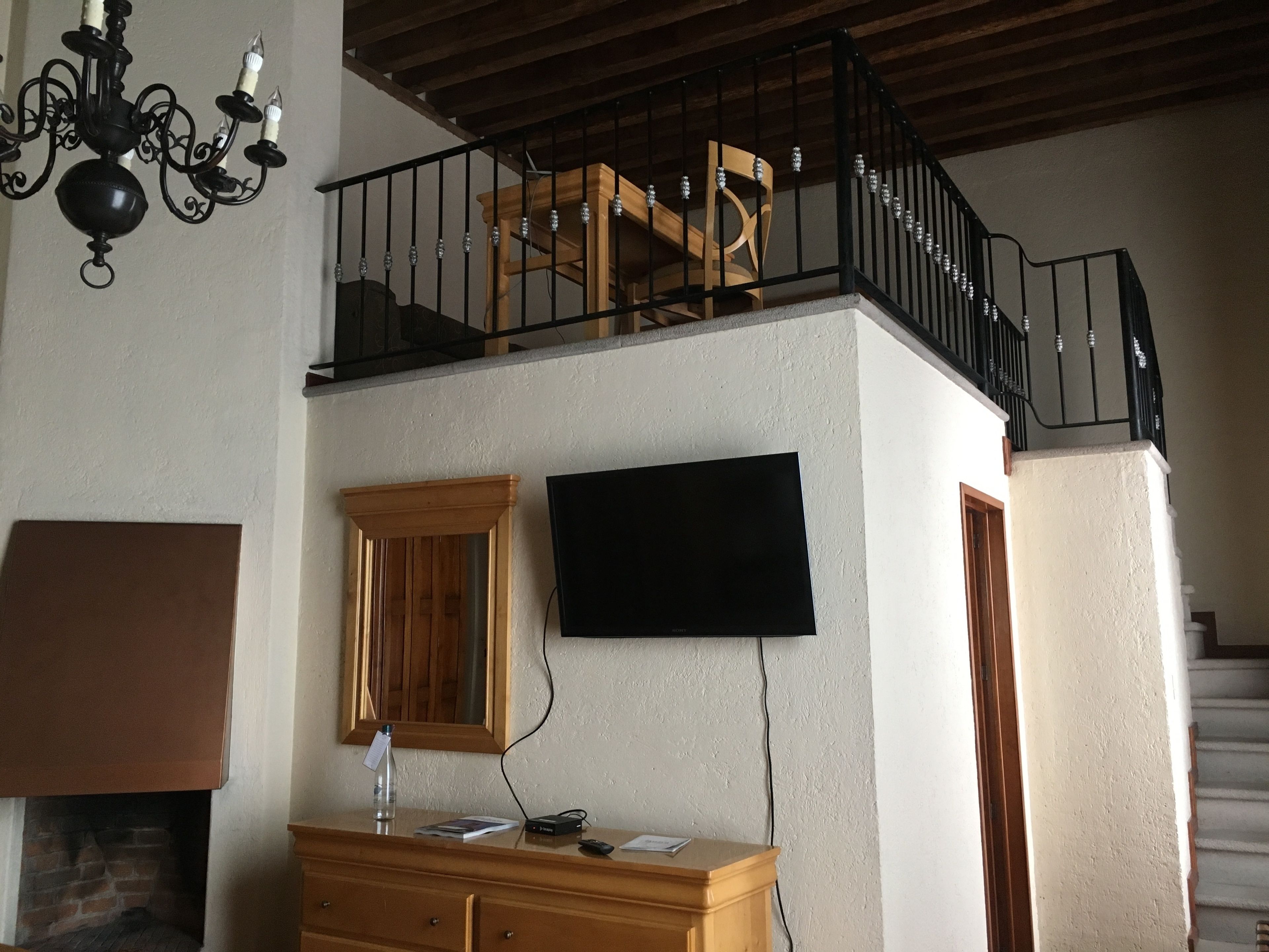 Una habitación con chimenea, cómoda de madera y televisor montado en la pared.