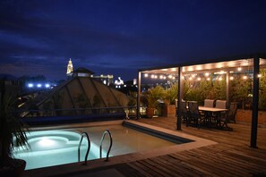 A rooftop pool area with a hot tub, outdoor seating, and a view of a cityscape at night. - Estrella de Belem (San Pedro Cholula)