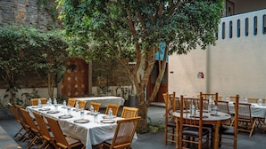 An outdoor dining area with multiple tables and chairs, surrounded by plants and a tree. - Estrella de Belem (San Pedro Cholula)