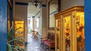 A stone-floored hallway with wooden beams, a large cabinet with glass doors, and a chandelier. - Estrella de Belem (San Pedro Cholula)