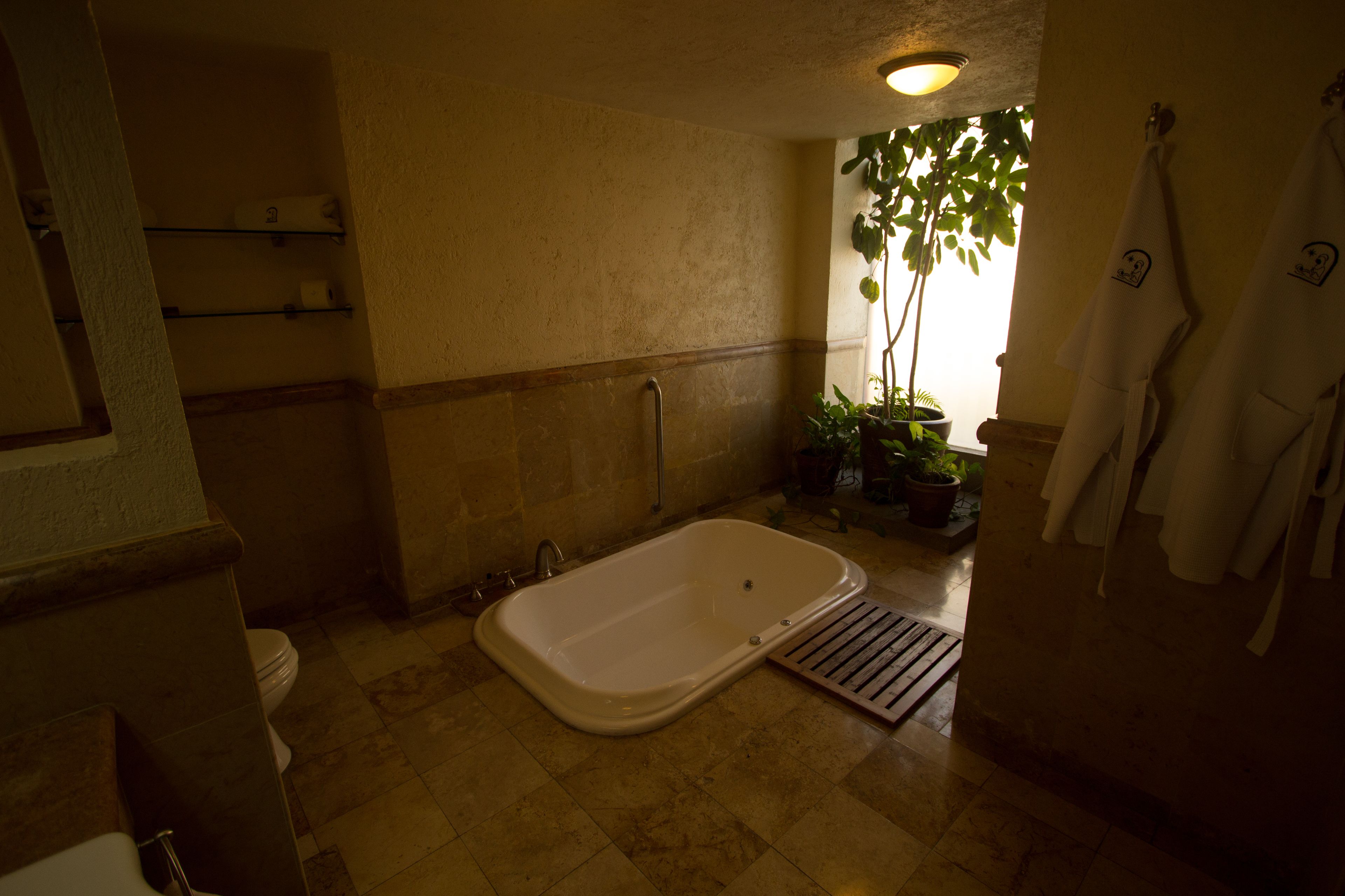 A bathroom with a bathtub, toilet, and shelves with toiletries.