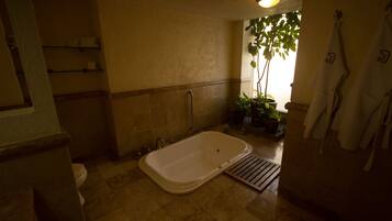 A bathroom with a bathtub, toilet, and shelves with toiletries.