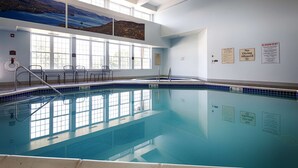 An indoor swimming pool with clear blue water, a diving board, and a lifeguard chair. - Best Western Plus Ticonderoga Inn & Suites (Ticonderoga)