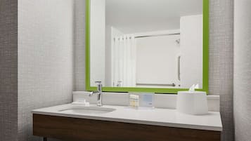 A bathroom with a large mirror, a sink, and a towel dispenser.