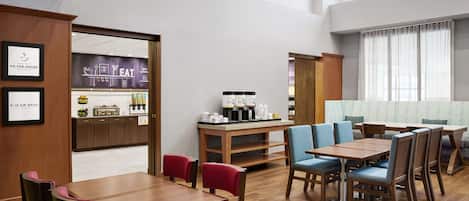 Un vestíbulo de hotel con una barra de café, zona de estar y vistas de la ciudad.