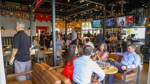 Un restaurante con asientos tipo banca de cuero, múltiples televisores y un ambiente informal para comer.