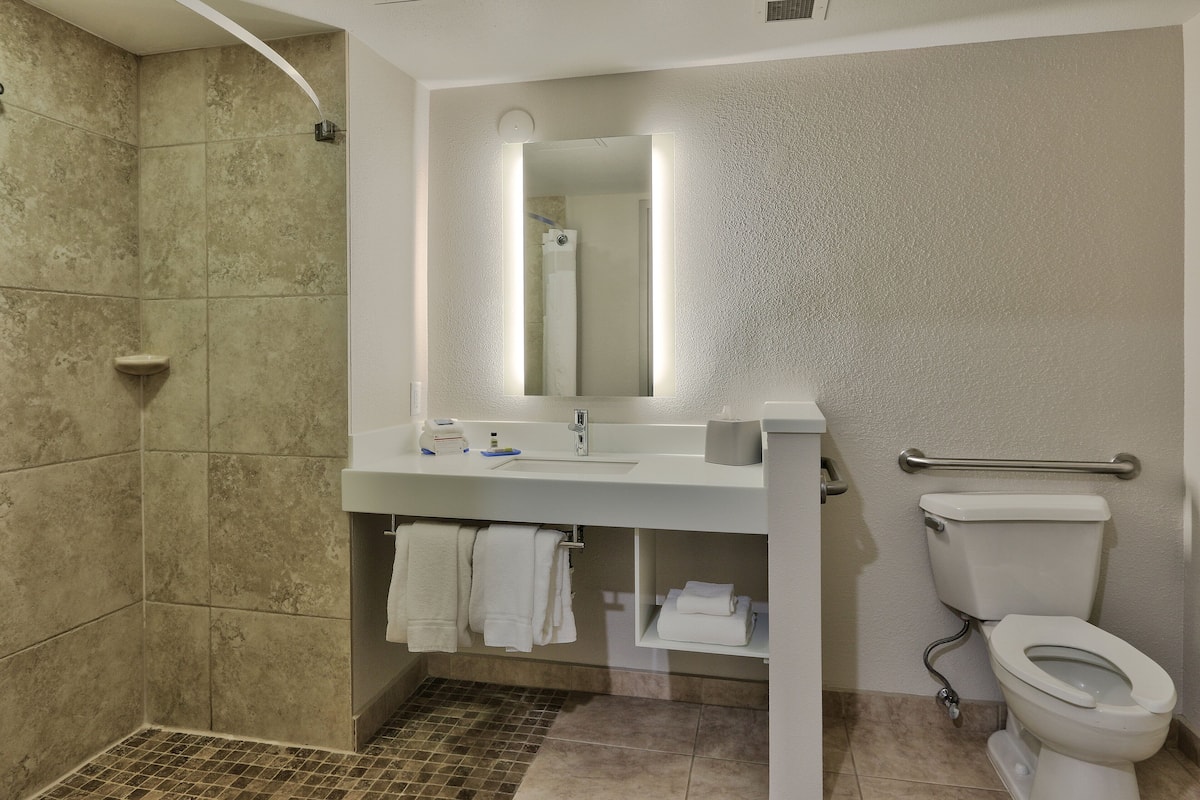 A modern bathroom with a shower, sink, and toilet.