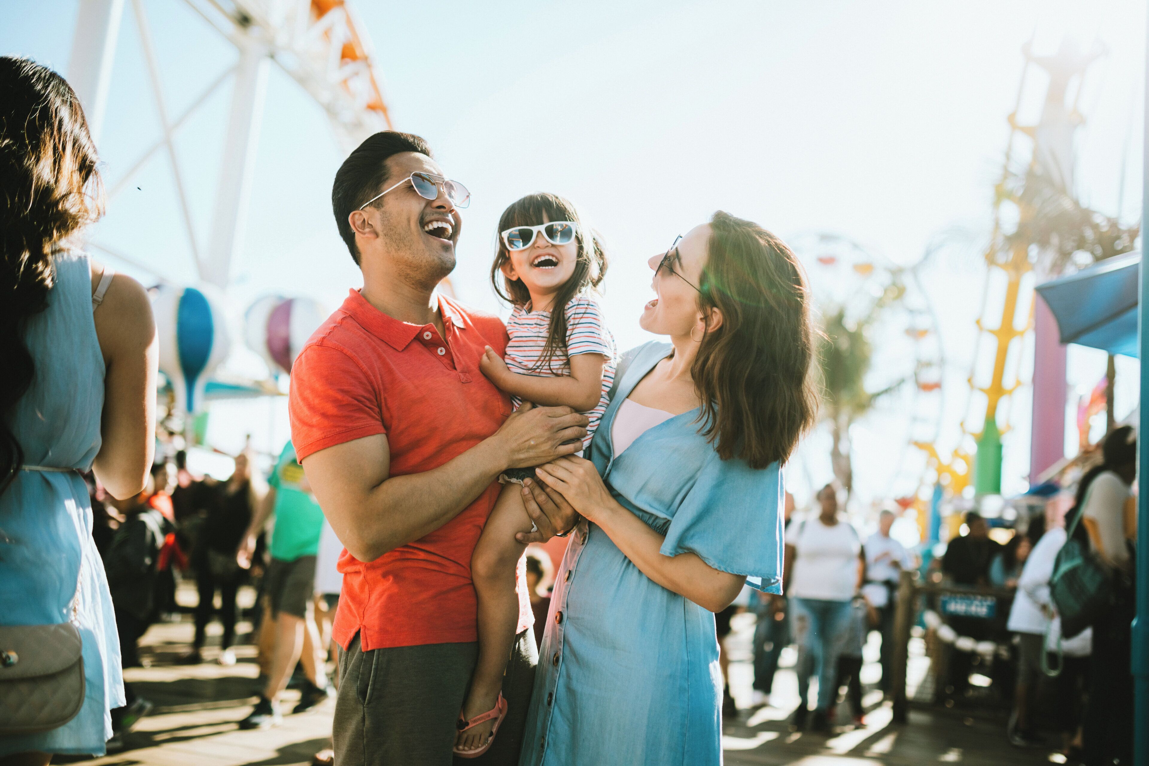 A family at an outdoor event with a Ferris wheel in the background.