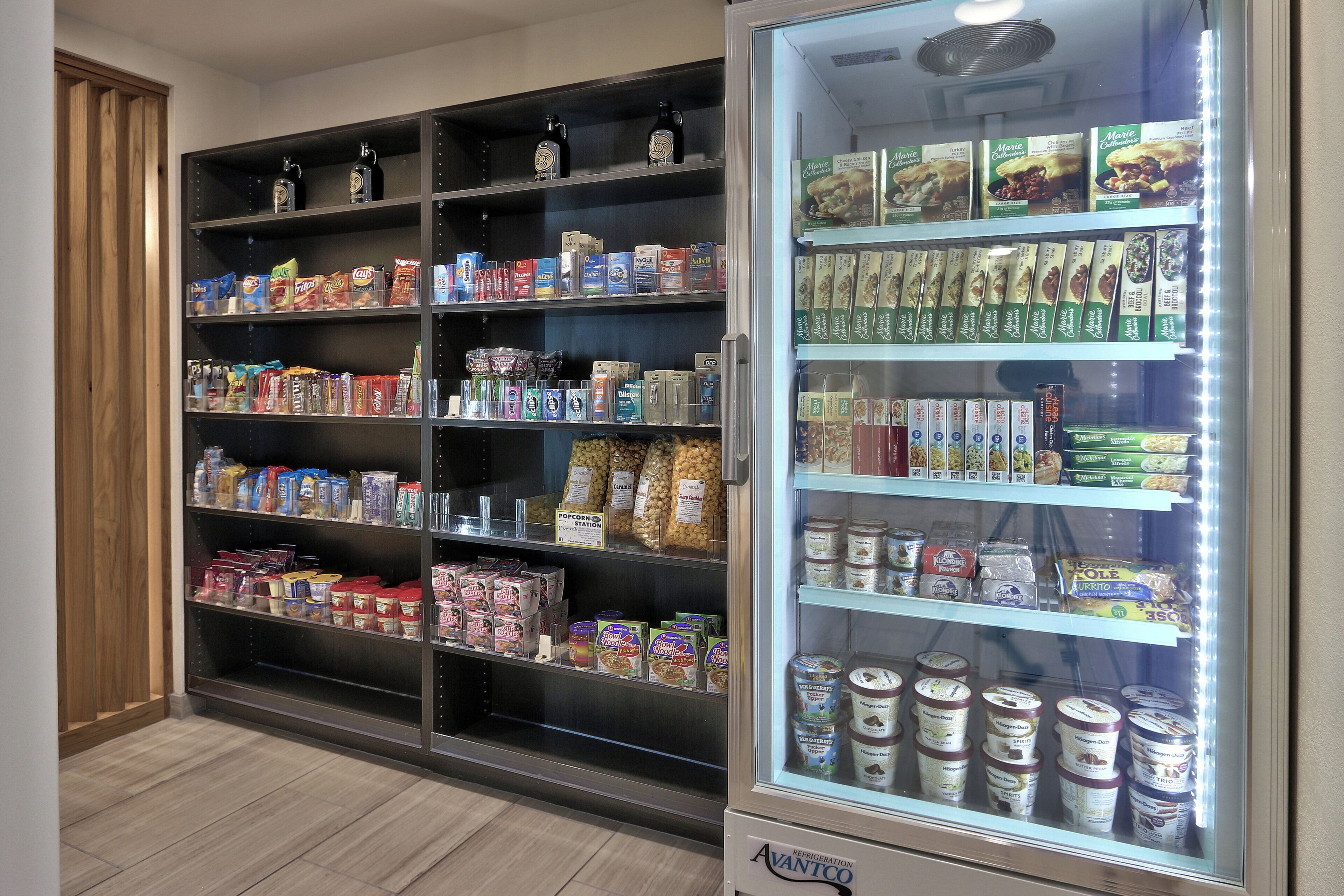 A refrigerated display case with various food items and a freezer section with packaged goods.
