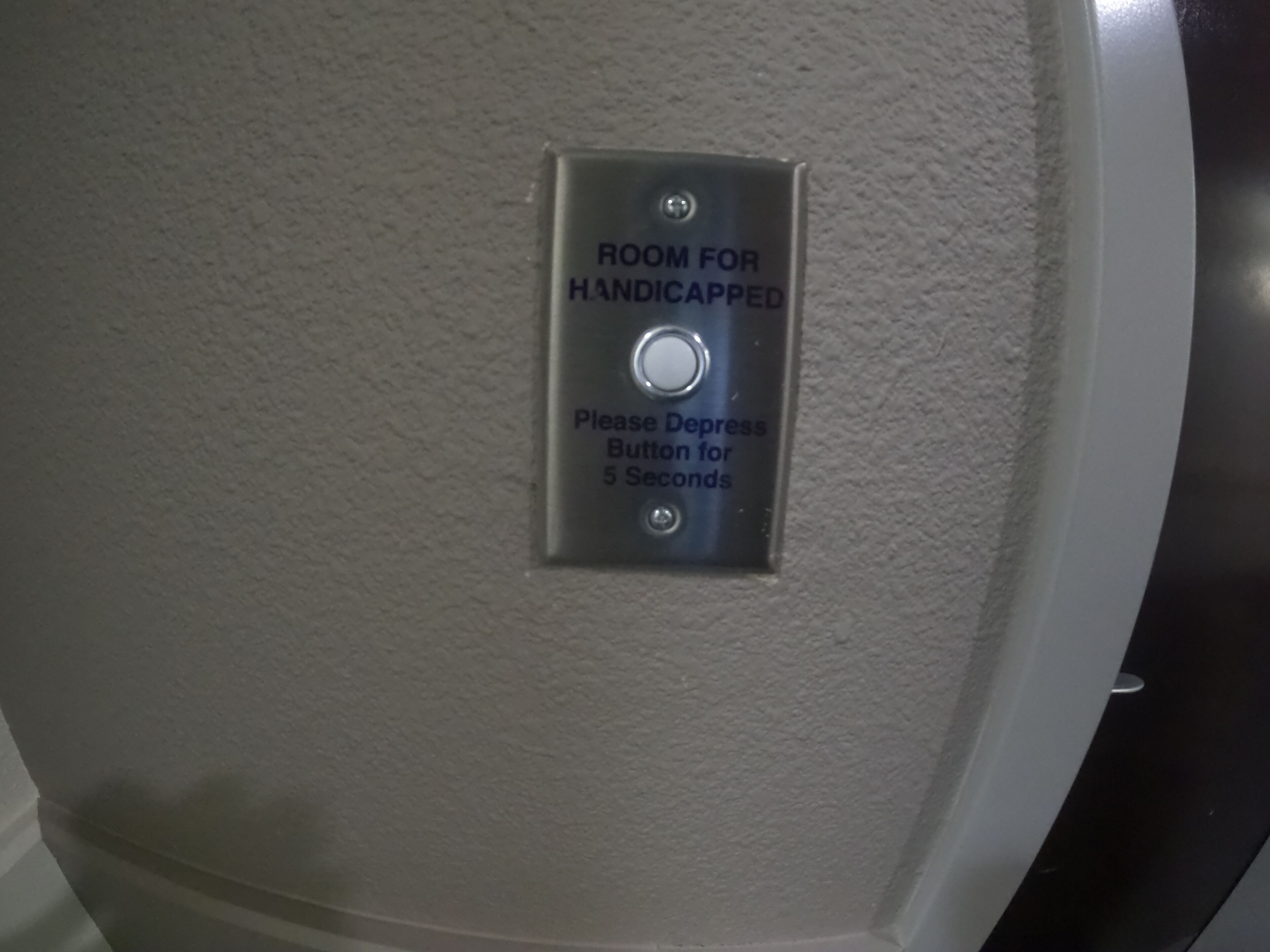 A sign indicating a room for handicapped individuals with a depress button for 5 seconds.