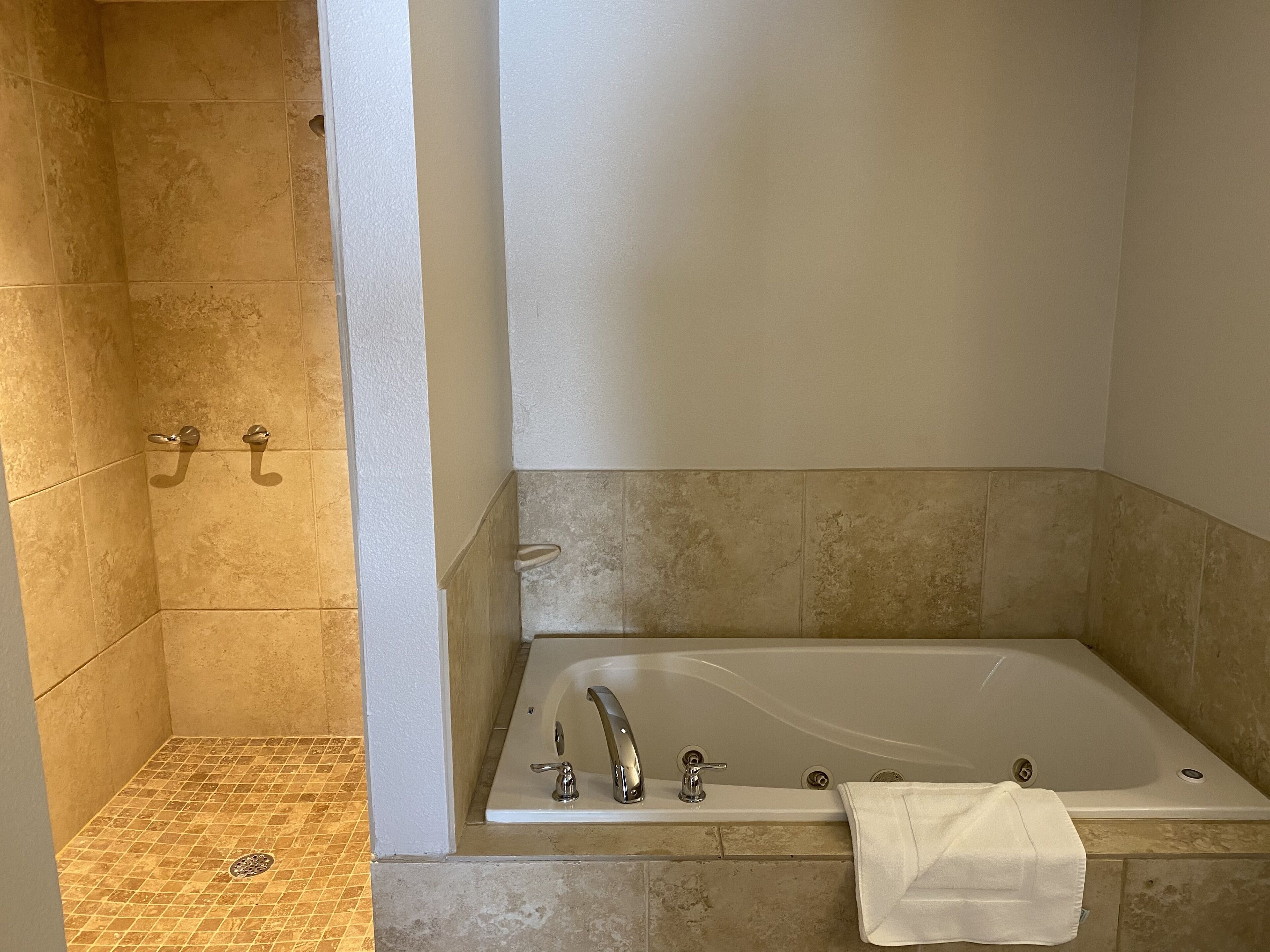 Ein modernes Badezimmer mit einer freistehenden Badewanne, einer Duschkabine mit Fliesenwänden und einem Handtuch an der Wand.