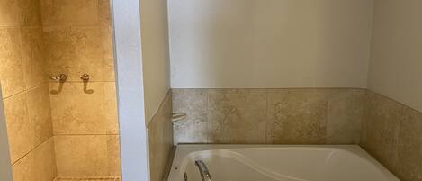 Ein modernes Badezimmer mit einer freistehenden Badewanne, einer Duschkabine mit Fliesenwänden und einem Handtuch an der Wand.
