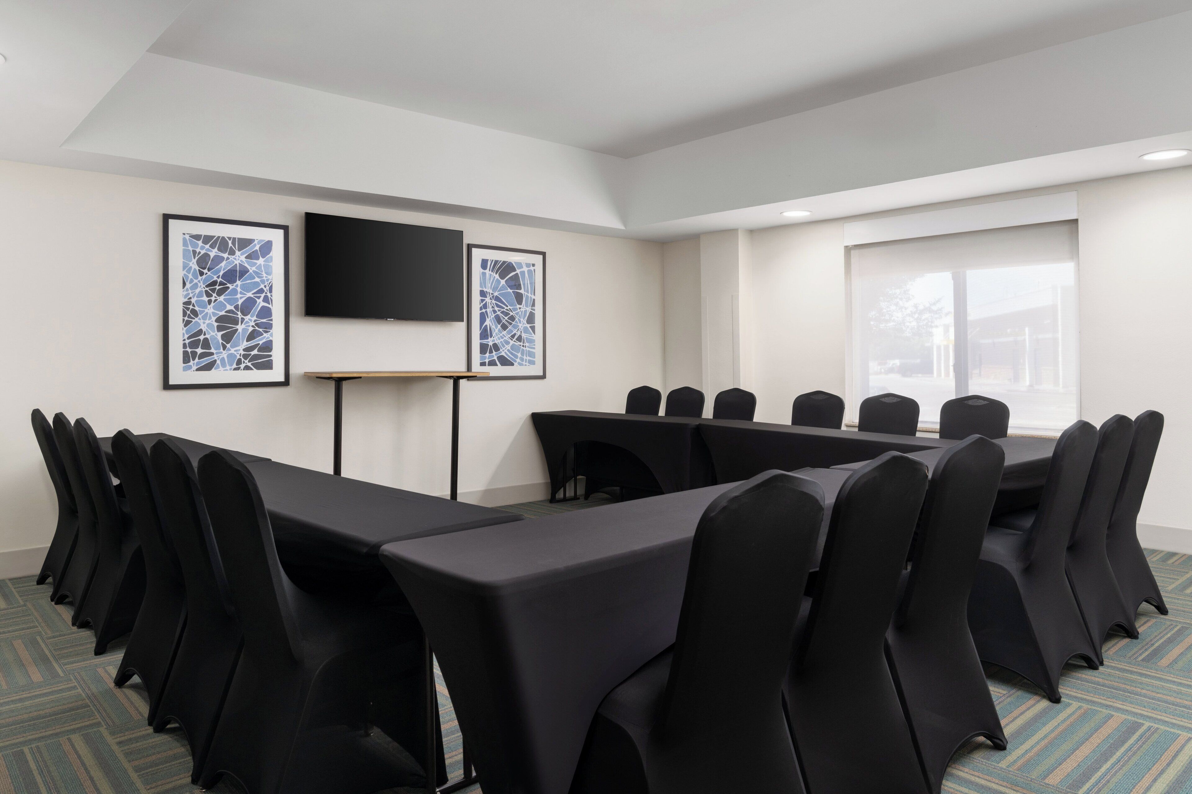 Una sala de conferencias con una larga mesa y sillas, un televisor de pantalla plana y obras de arte enmarcadas en las paredes.