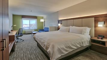 A hotel room with a large bed, a desk with a chair, a small table, and a window with a view.