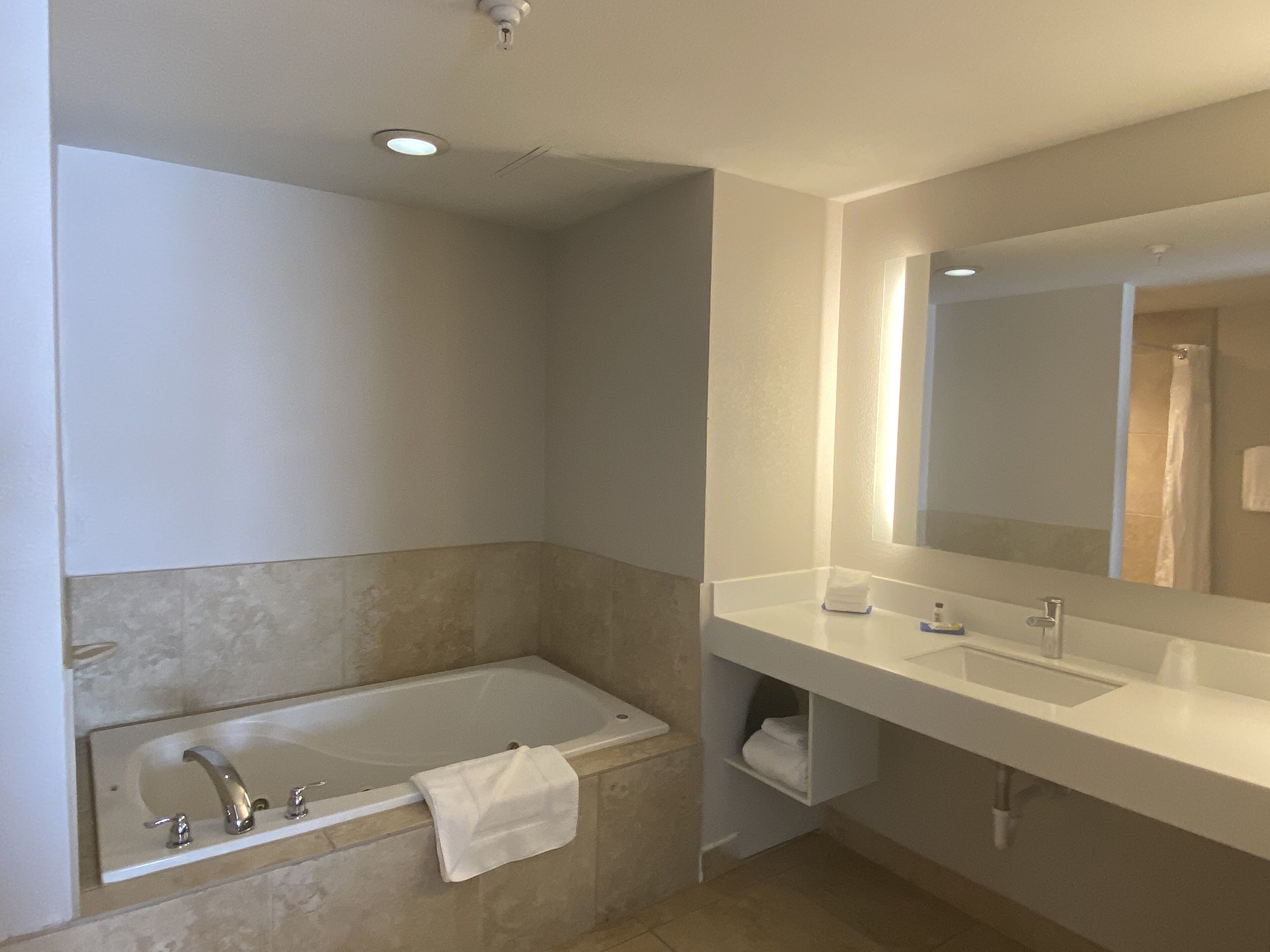 Un baño moderno con bañera, lavamanos y un espejo grande.