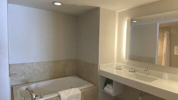 Un baño moderno con bañera, lavamanos y un espejo grande.