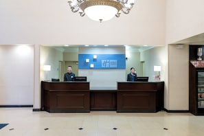 A hotel reception desk with two receptionists, a chandelier, and a sign indicating the hotel name. - Holiday Inn Express Los Angeles Airport Hawthorne by IHG (Hawthorne)