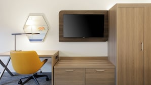 A modern room with a desk, a yellow chair, a flat-screen TV, and a wooden wardrobe. - Holiday Inn Express Los Angeles Airport Hawthorne by IHG (Hawthorne)